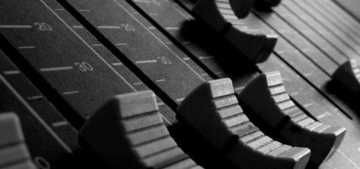 Close-up of faders on an audio mixing console with decibel markings.