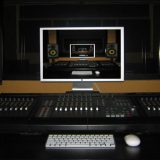 Audio mixing console and studio speakers around a screen displaying an infinite recursive loop of the setup.