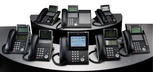 Eight black office desk phones with digital display screens arranged in two rows on a curved surface.