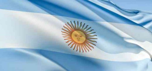 The national flag of Argentina with light blue and white stripes and a golden sun waving in the wind.
