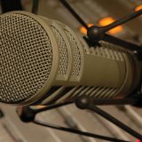 Studio microphone in a shock mount positioned above an audio mixing console.