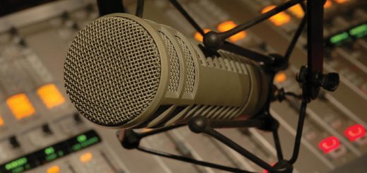 Studio microphone in a shock mount positioned above an audio mixing console.