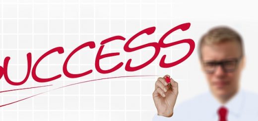 A man in glasses writes the word SUCCESS in red marker on a transparent surface.
