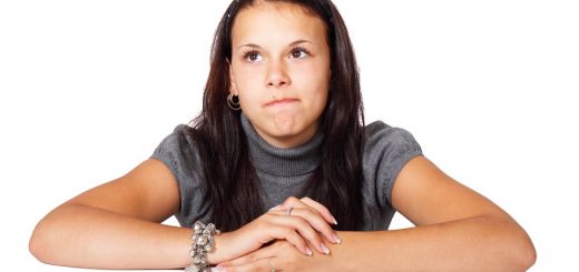A young woman leaning on her arms with a pensive expression against a white background.