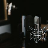 A professional condenser microphone with a shock mount and pop filter in a studio.
