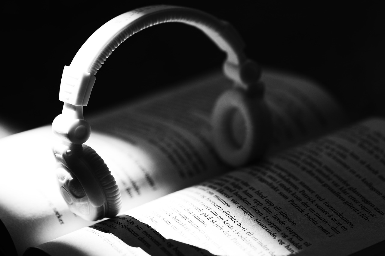 White headphones resting on the pages of an open book under focused light.