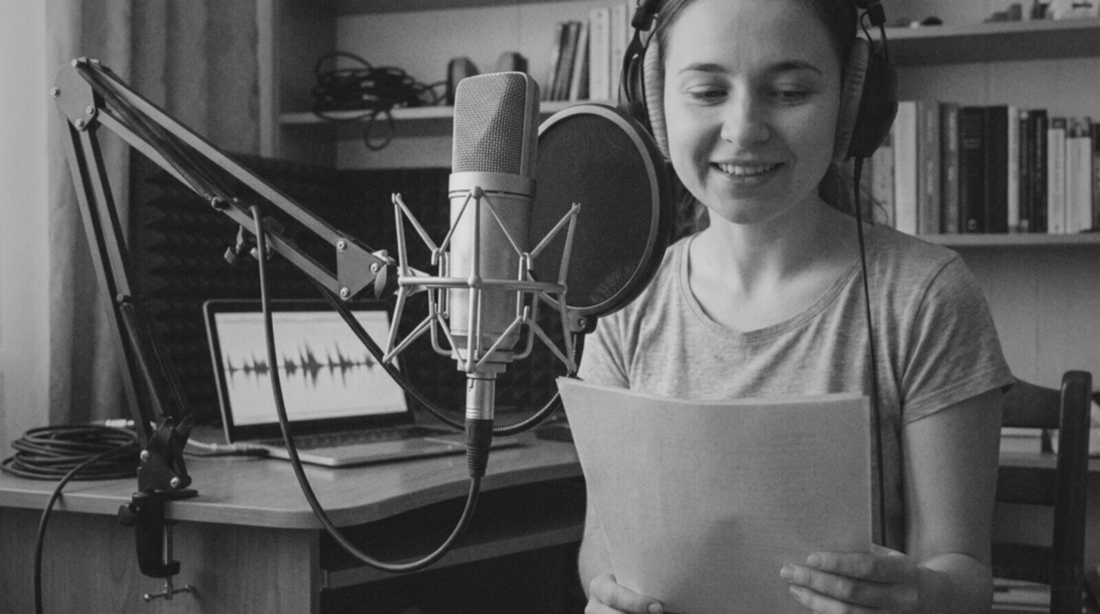 A beginner voice actor reading a script aloud in a small home studio corner © The Voice Realm