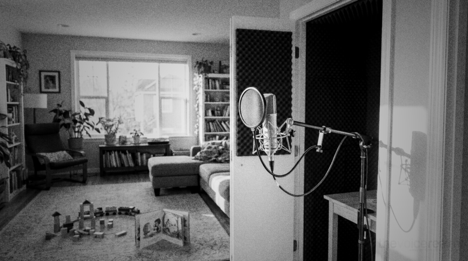 A family living room with toys on the rug and a small home recording booth behind an open door © The Voice Realm