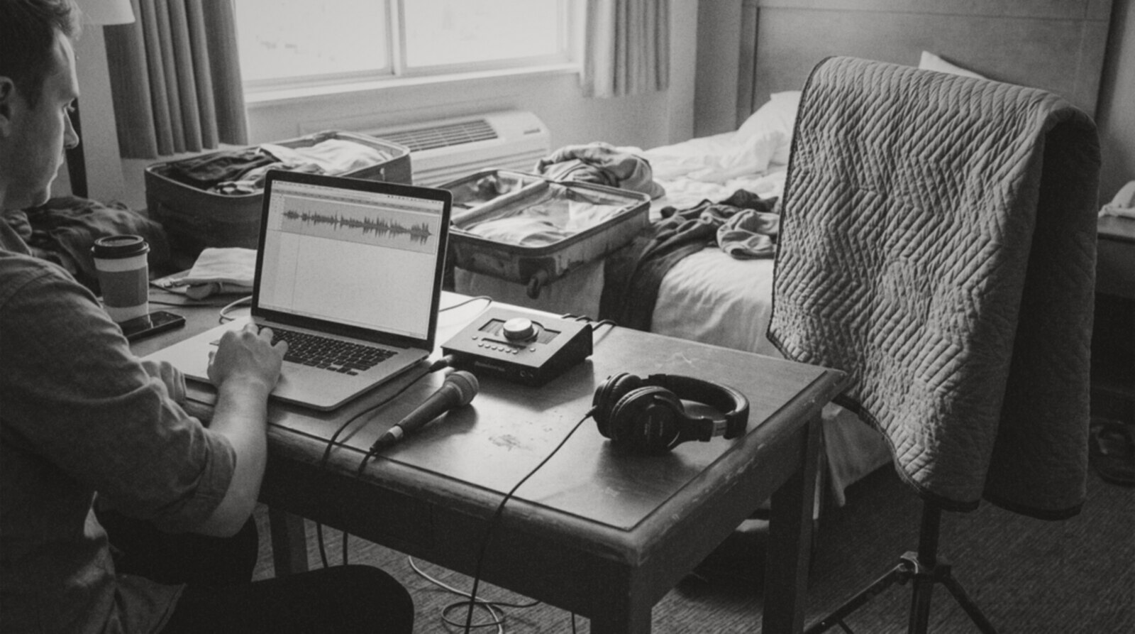A voice actor recording on a laptop and portable mic set up in a hotel room © The Voice Realm