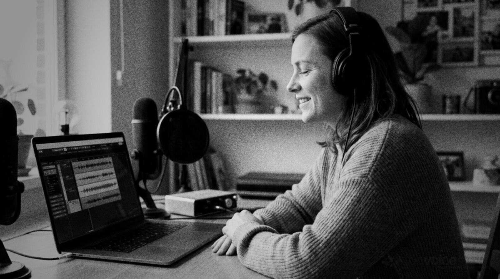A smiling voice actor listening back to a demo edit in her home studio © The Voice Realm