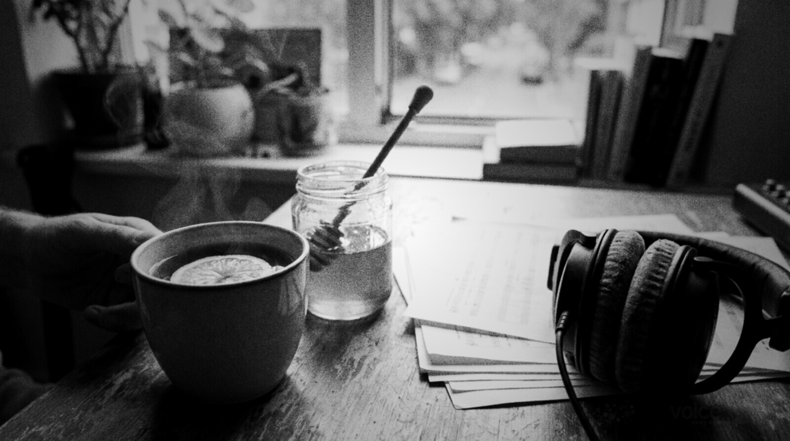 A mug of warm lemon tea and a jar of honey beside a script and studio headphones © The Voice Realm
