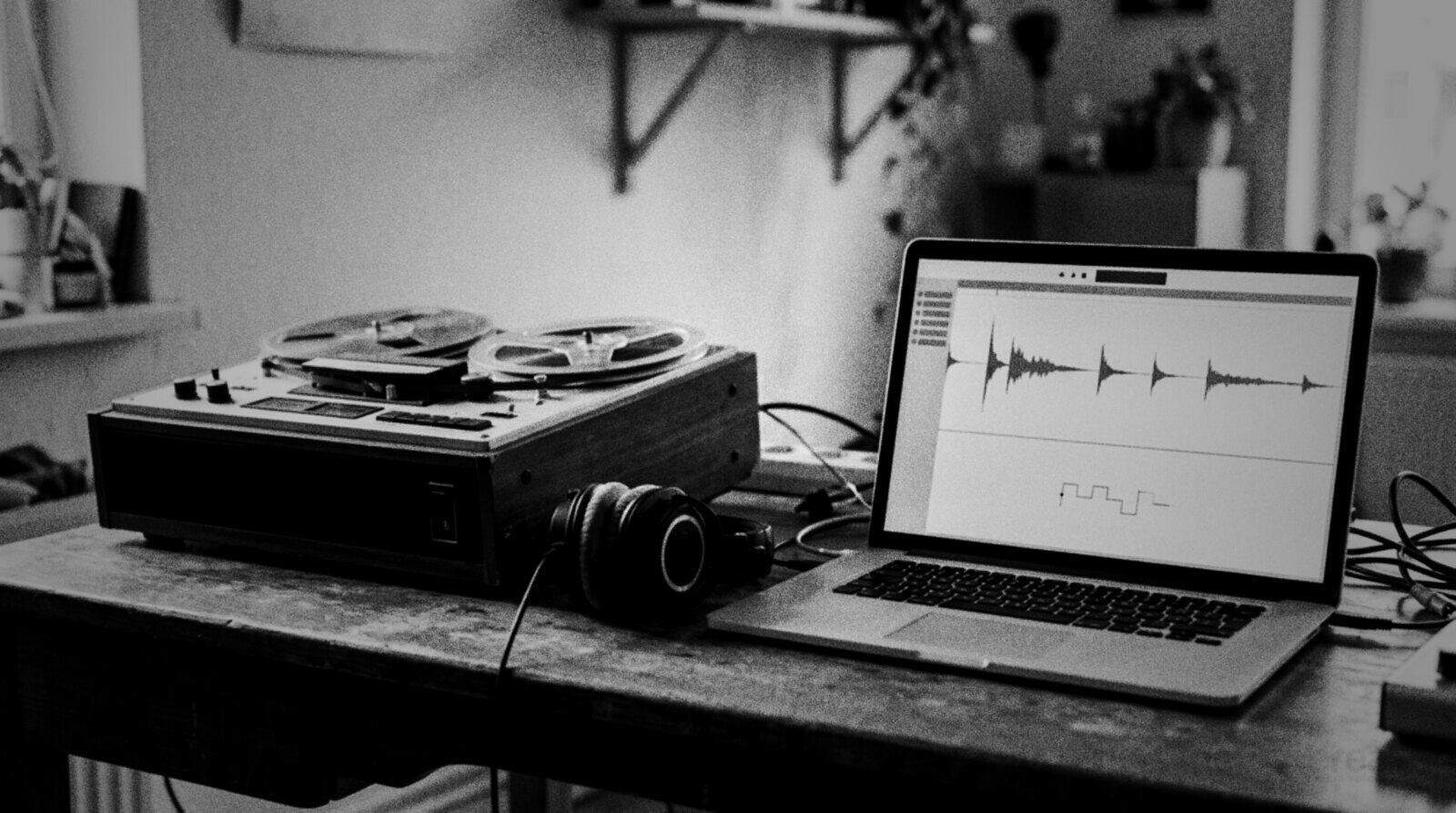 An old reel-to-reel tape recorder next to a modern laptop showing an audio waveform on one studio desk © The Voice Realm