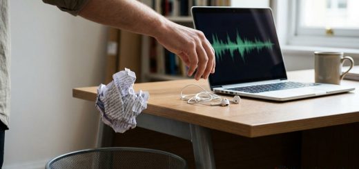 A hand dropping a crumpled script into a wastepaper bin beside a laptop showing an audio waveform © The Voice Realm