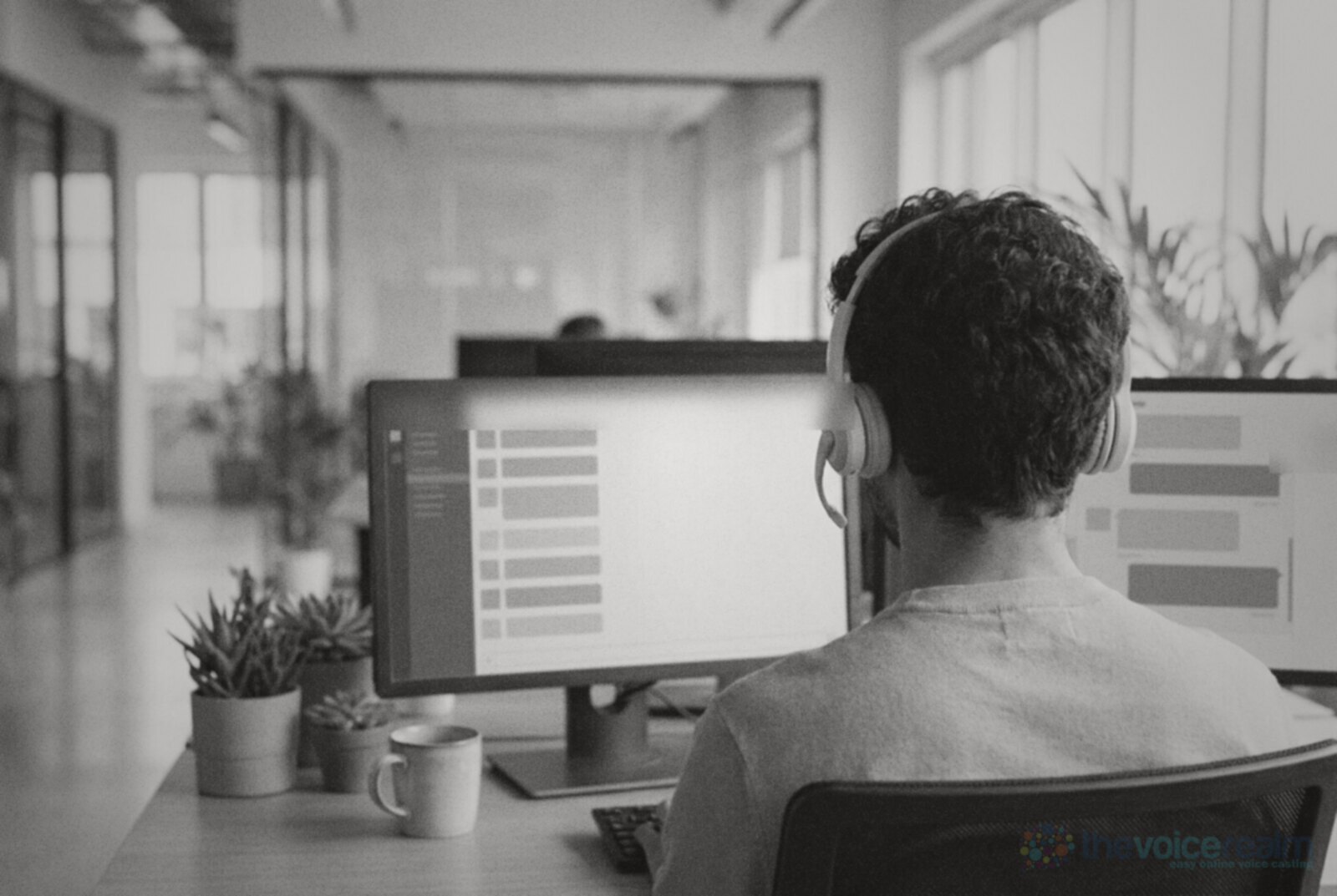 A support staffer in a headset seen from behind, working at two monitors showing a list of jobs and a message thread © The Voice Realm