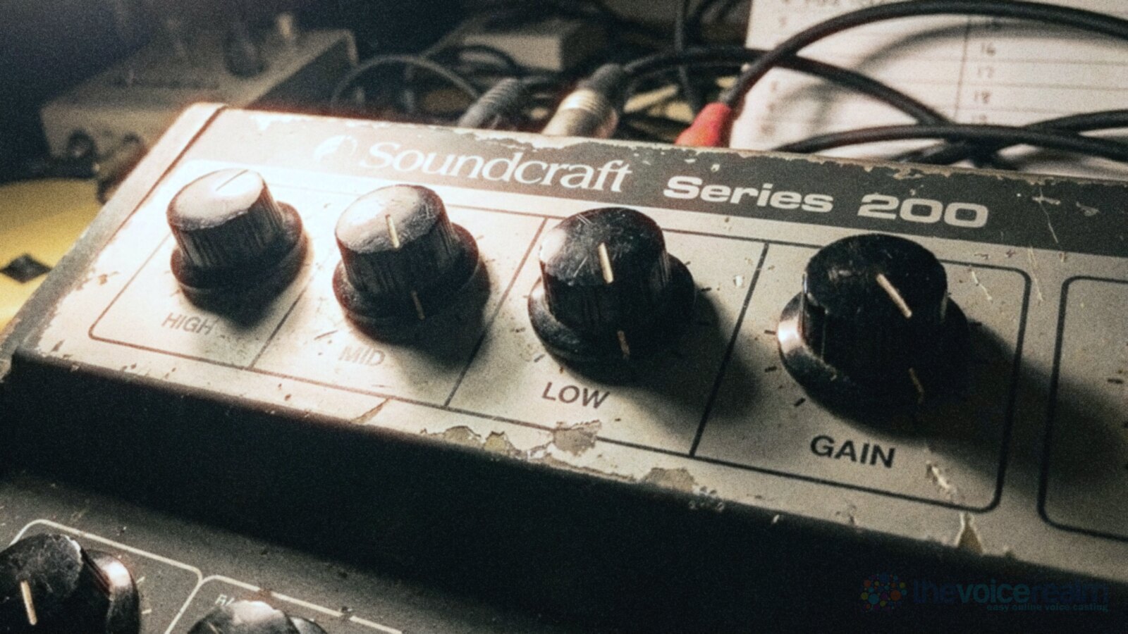Close-up of the HIGH, MID, LOW and GAIN knobs on a worn Soundcraft Series 200 mixing desk in a home studio at night, lit from the side by a desk lamp © The Voice Realm