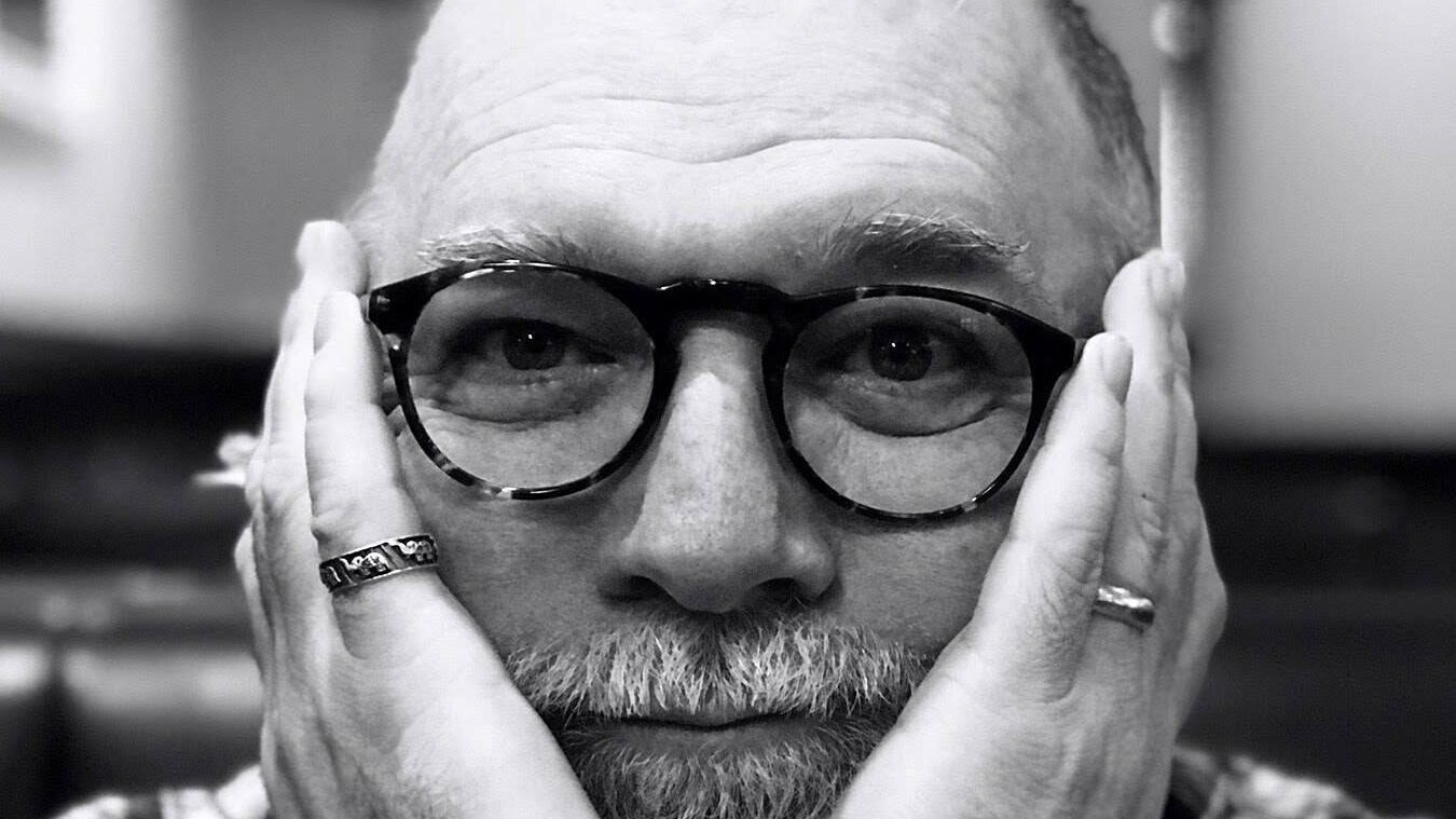David Atwood, a Southern male voice actor from New Orleans, in his trademark round glasses, hands framing his face. Photo courtesy of David Atwood